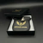 Bitcoin Angel figurine in a black box with gold logo on a dark background