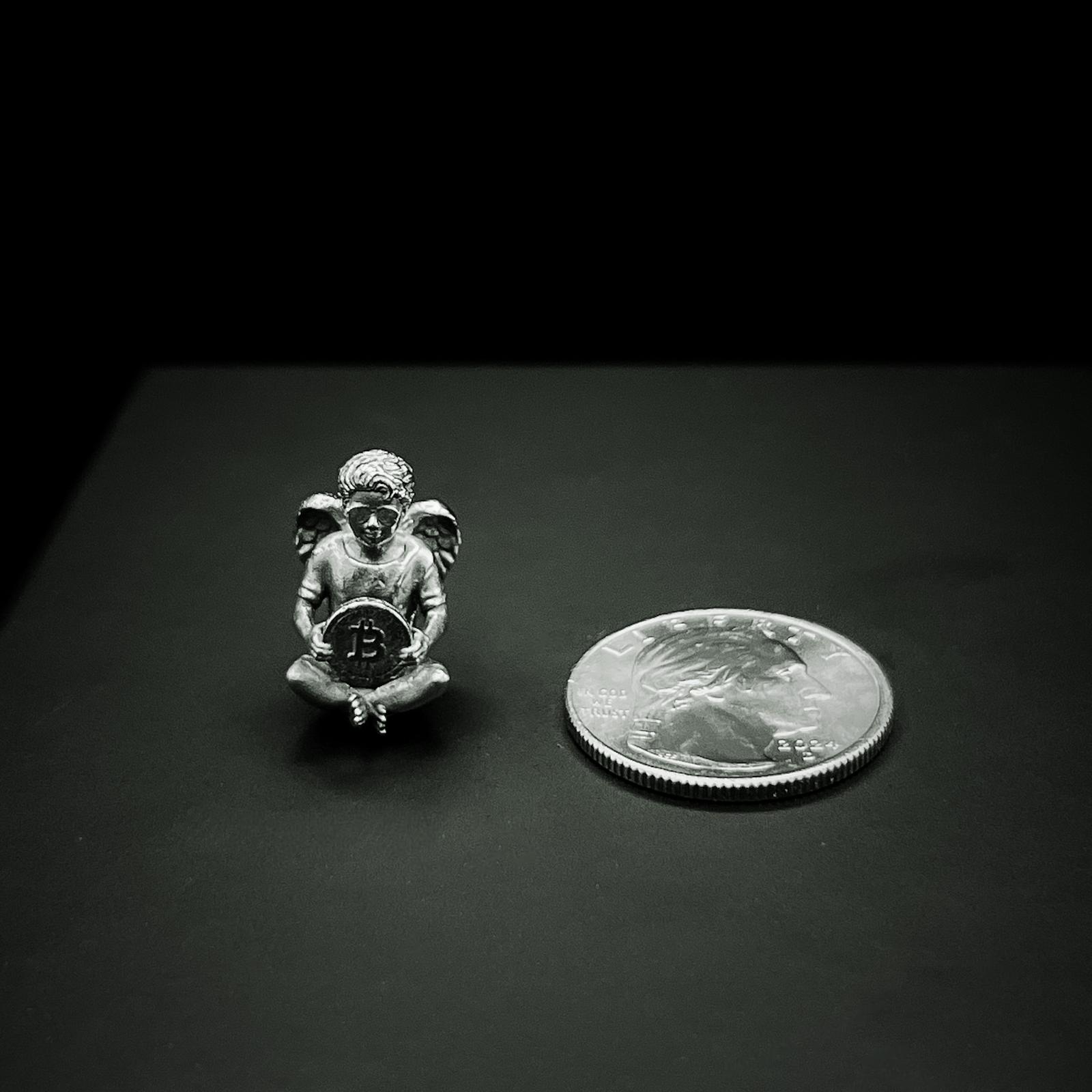 Small silver Bitcoin Angel figure with a coin on a dark surface